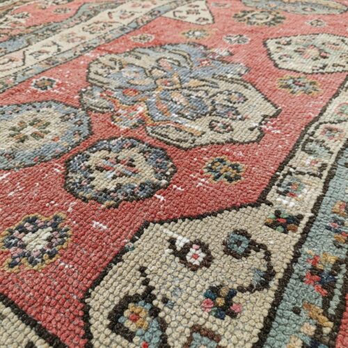 A faded red handmade carpet with faded colours