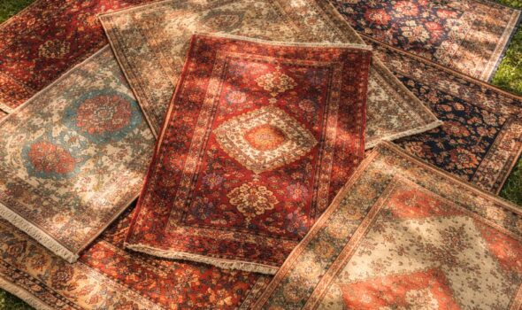 Vintage handmade rugs layered on grass with sunlight and shadows top view